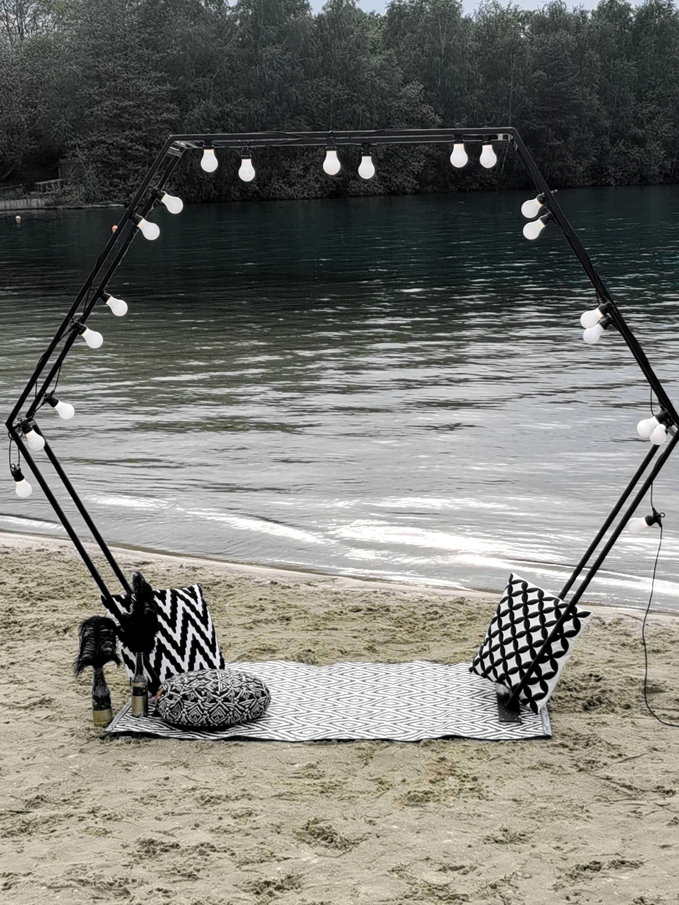schwarzer Traubogen Hexagon aus Metall am Strand mit Lichterkette dekoriert