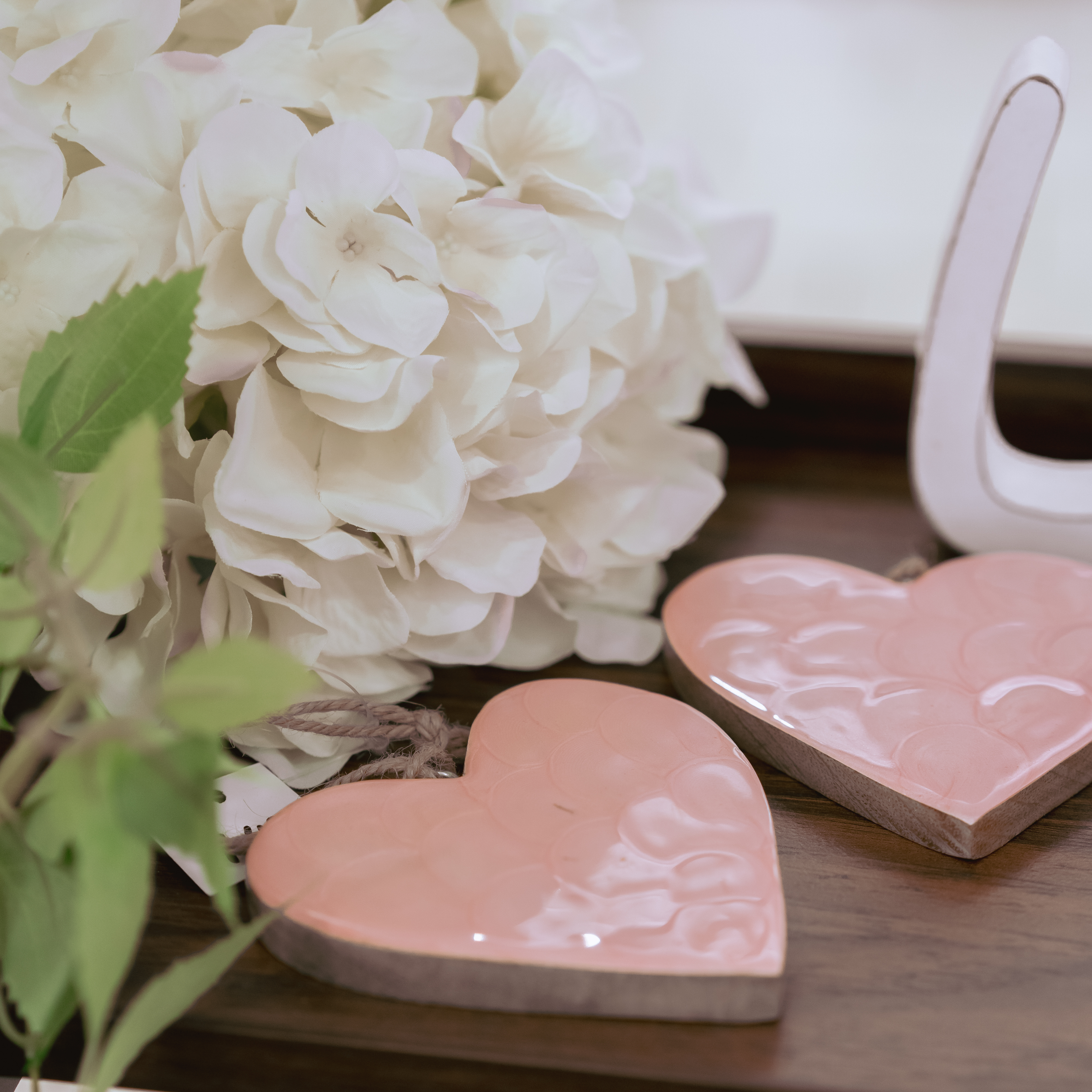 2 rosa Herzen auf Holztisch gelegt mit Blumendeko